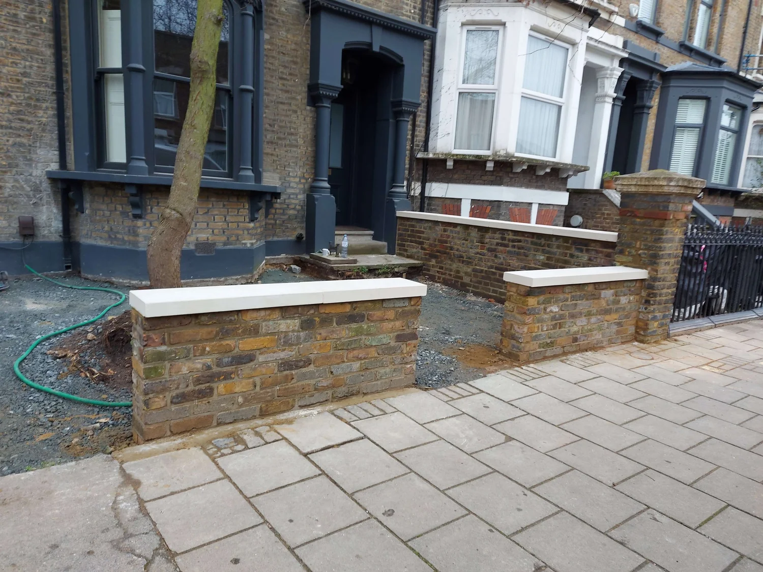 Restored brick wall front view showing clean bricks and new sandstone coping