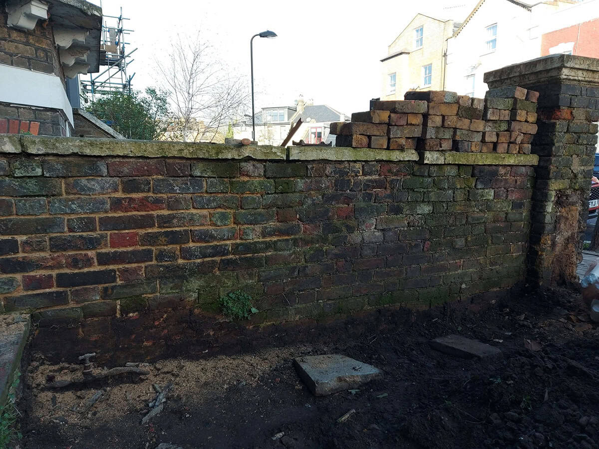 Weathered brick wall before restoration showing moss, dirt, and deteriorated mortar