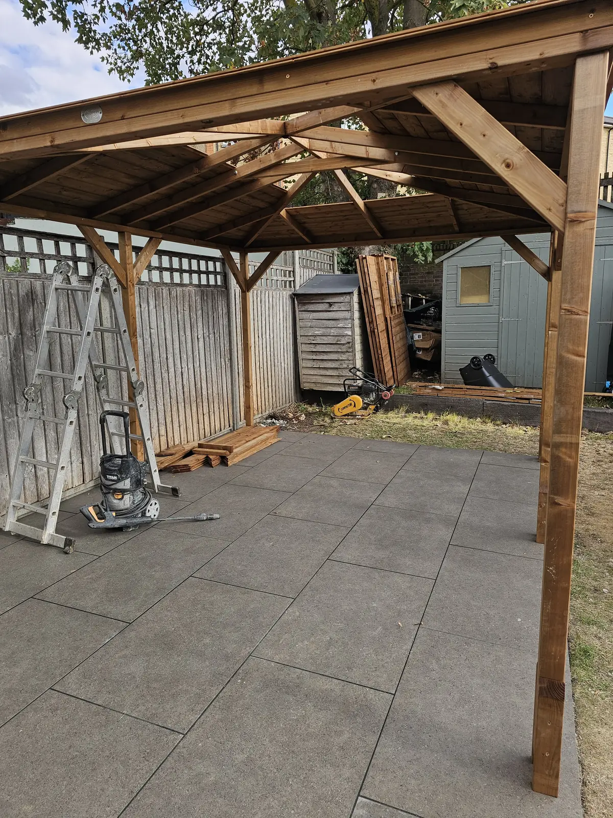 Porcelain patio laid with the timber gazebo frame going up behind it