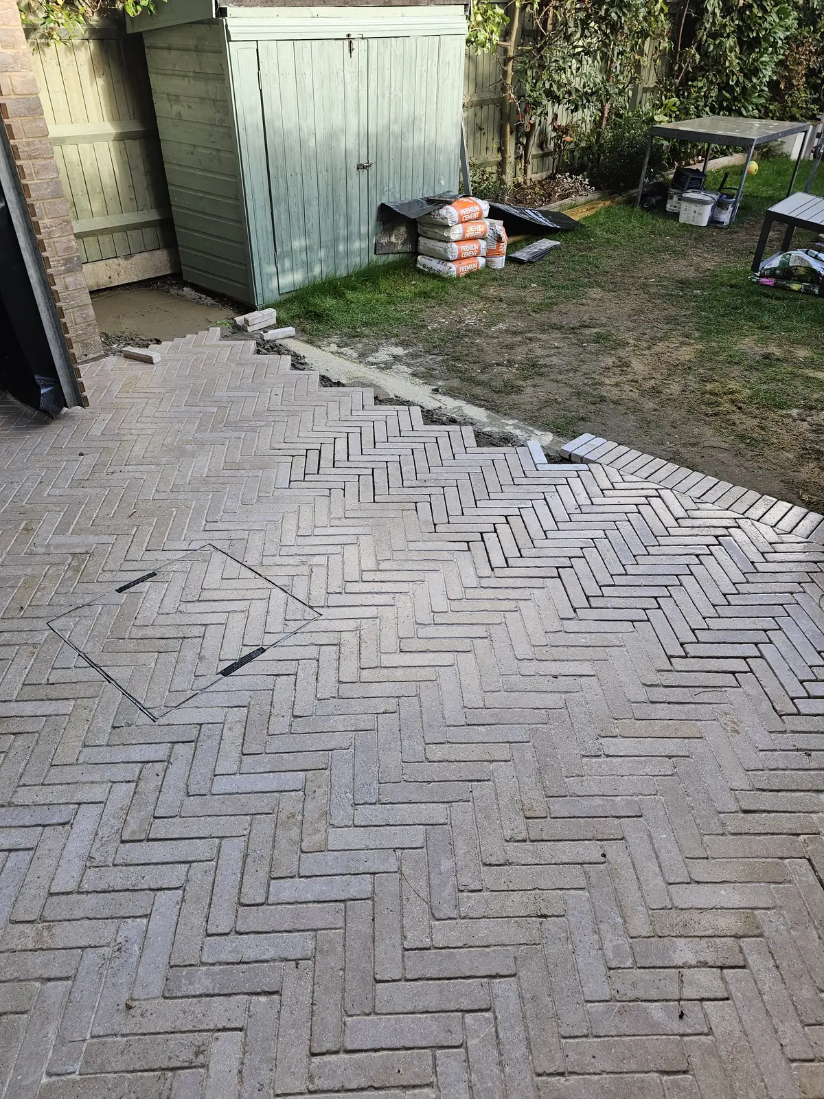 Herringbone limestone pavers laid across the patio towards the garden shed