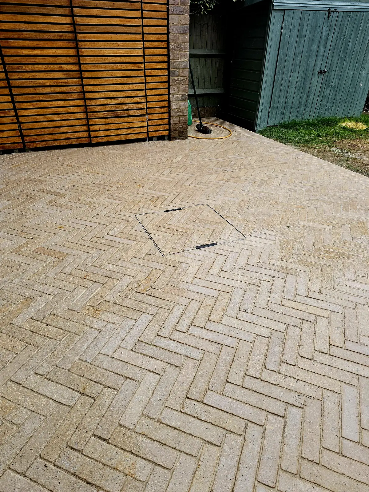 Finished herringbone limestone patio in Stratford with a timber slat screen and a pave-in inspection cover