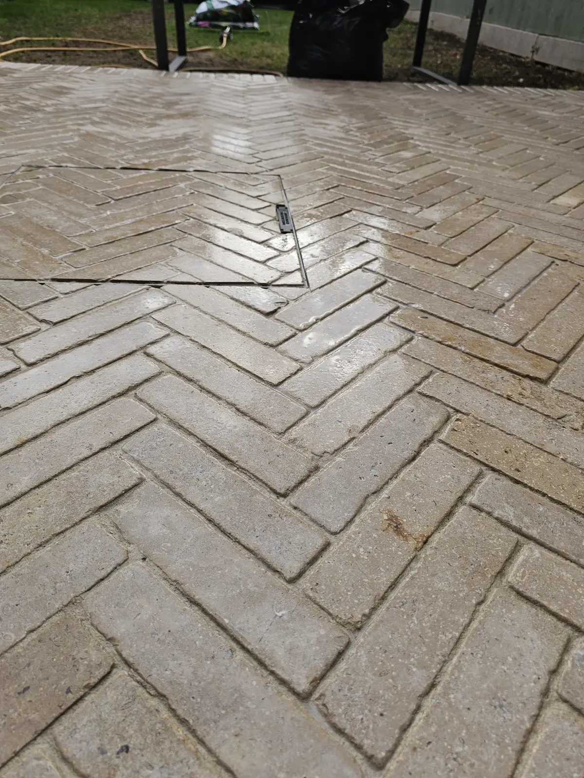 Pave-in inspection cover with the herringbone pattern running straight through it, after sealing