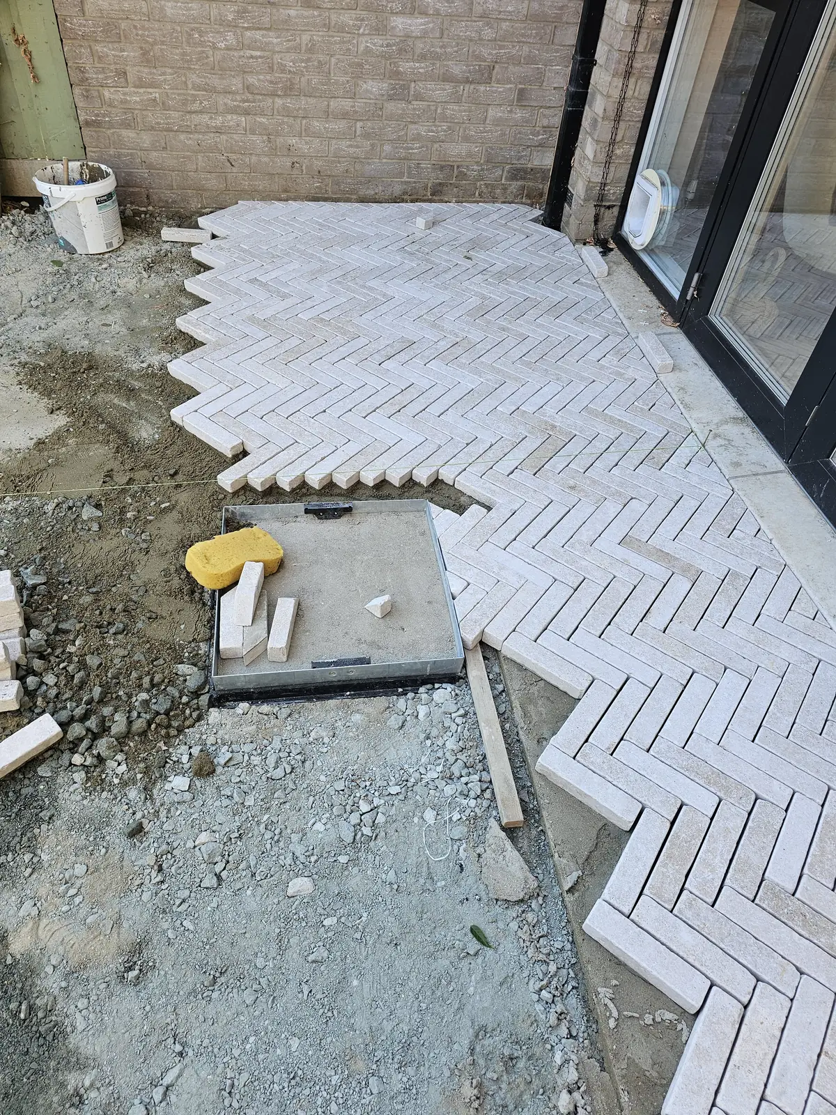 Pave-in inspection cover tray ready to be filled with pavers to match the herringbone pattern